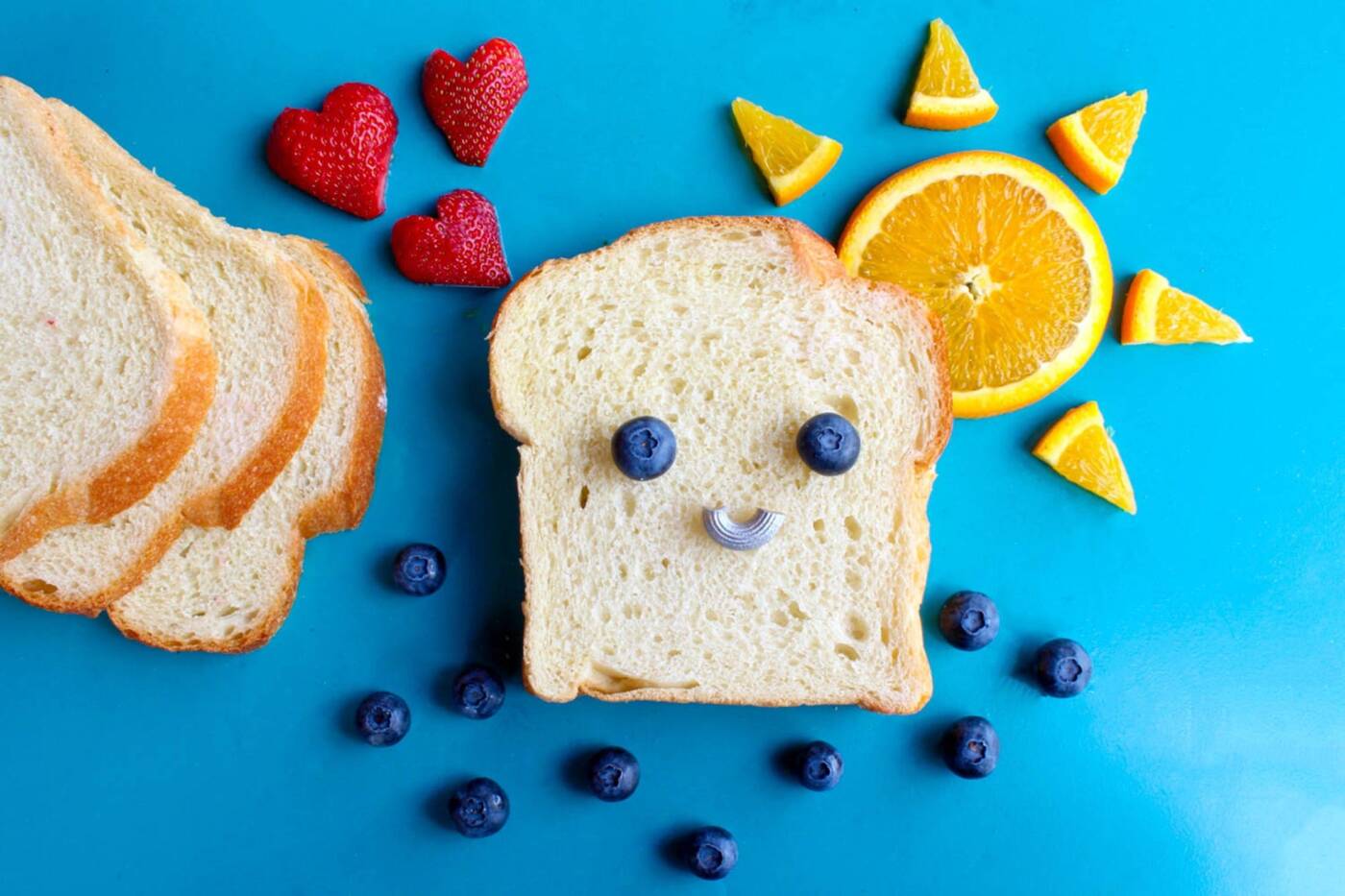 A slice of white bread with a blueberry smiling face.